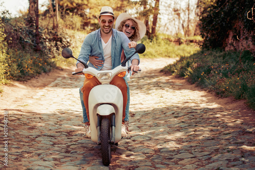 Happy young couple riding a scooter in the city photo