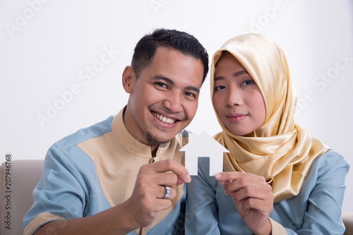 muslim asian couple holding home sign