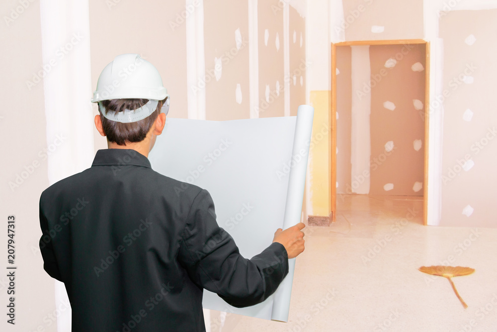 engineering businessman hold paper blueprint check gypsum board wall interior decoration of home in construction site engineering businessman hold paper blueprint check gypsum board wall interior decoration of home in construction site