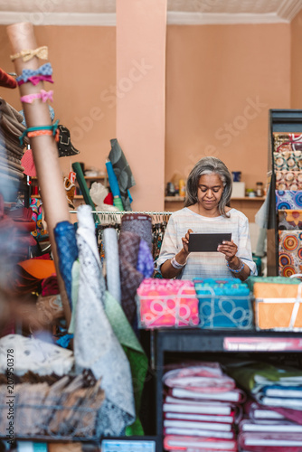 Mature woman working with a tablet in her fabric shop © mavoimages