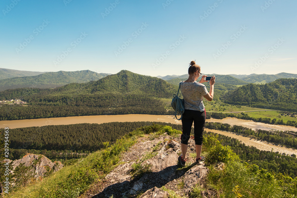 Fototapeta premium Woman taking photo on mobile phone at the mountain peak.