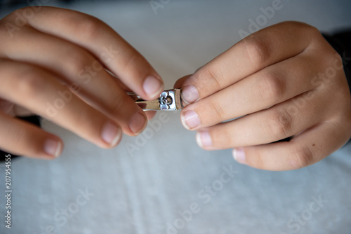 Hands of the child with nail clipper, clipping the nails on his own