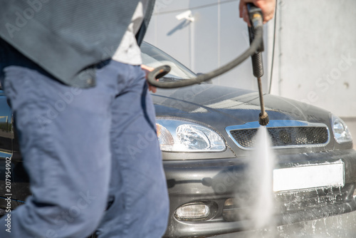 carwash concept. washing car with high presser water gun