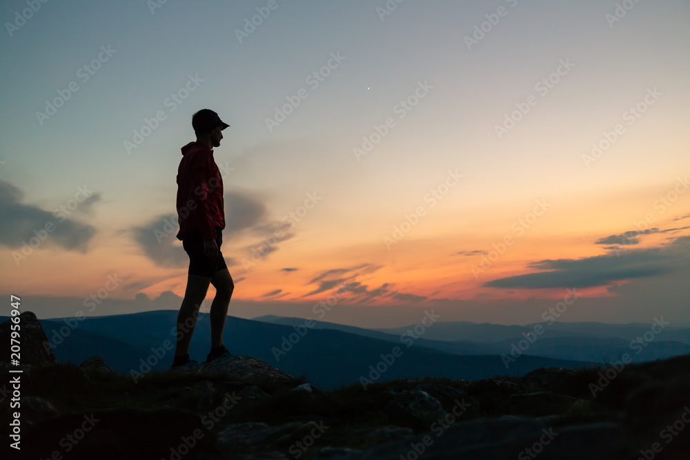 Man celebrating sunset looking at view in mountains