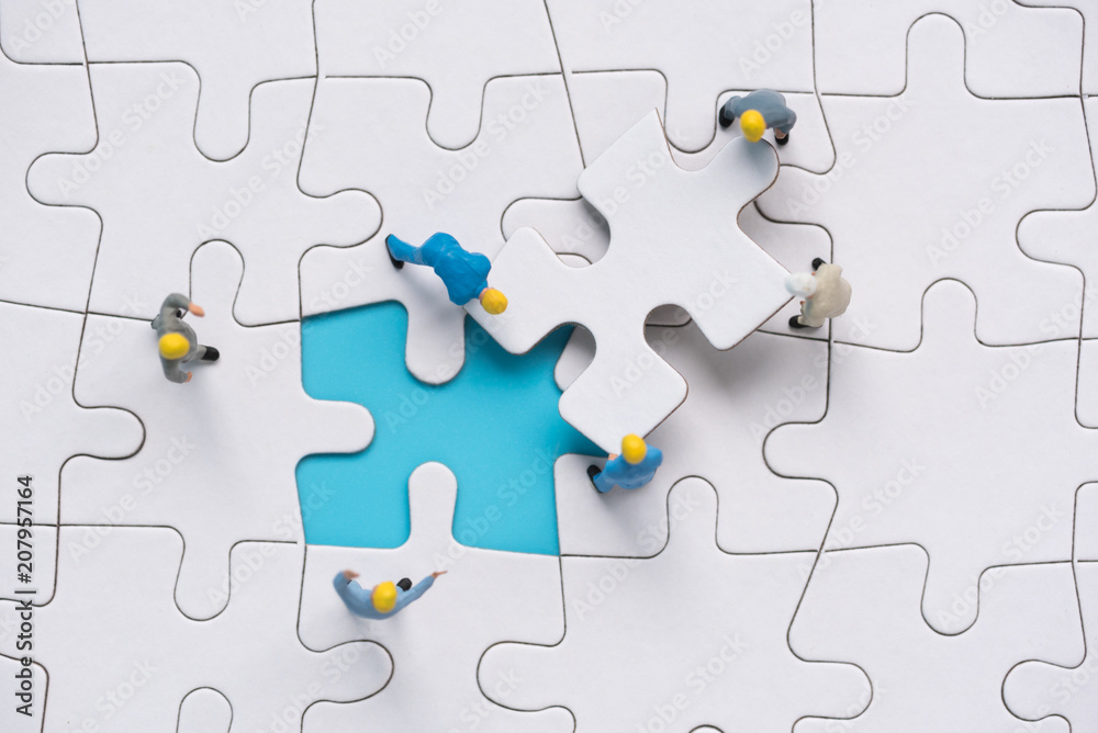 miniature people team trying to complete the last jigsaw puzzle piece , teamwork concept miniature people team trying to complete the last jigsaw puzzle piece , teamwork concept