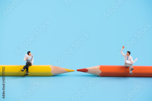 miniature people sitting on a pencil