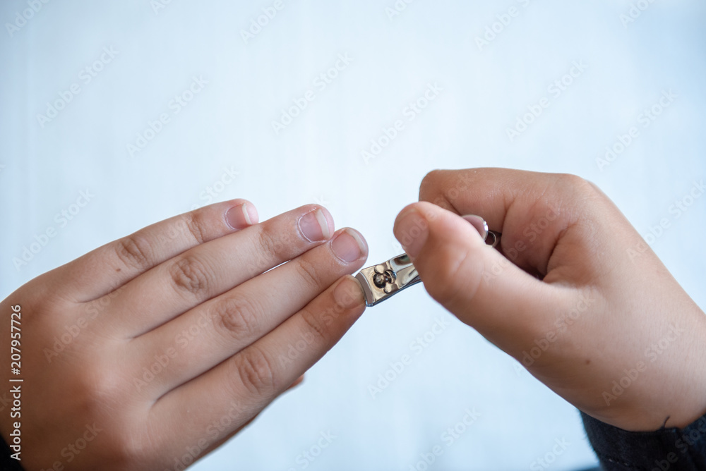 Hands of the child with nail clipper, clipping the nails on his own Hands of the child with nail clipper, clipping the nails on his own