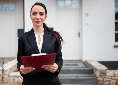 Real estate agent in front of house for sale ready to presenting offer, copy space photo