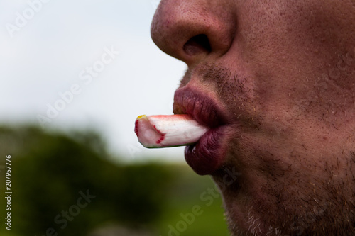 Close up view of young man's mouth eating fresh scallion or cany. Food photo concept. Unknown male chewing chopped fresh green onion outdoors. Photo shoot of human's mouth.