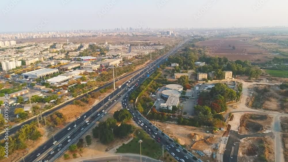 Aerial Highway Road Traffic View moving above Motorway Intersection with city skyline at the background Aerial Highway Road Traffic View moving above Motorway Intersection with city skyline at the background