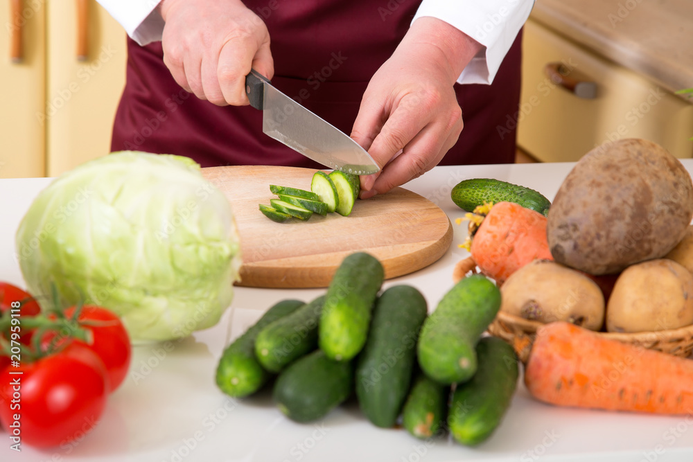 Preparation of vegetable salad. Close-up of a man's hand with a knife chopped cucumber. Preparation of vegetable salad. Close-up of a man's hand with a knife chopped cucumber.