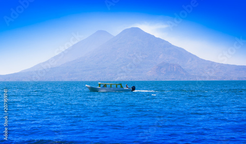 Beautiful outdoor view of small boats in Atitlan Lake is the deepest lake in all of Central America with a maximum depth of about 340 meters, with volcano in Background in Guatemala photo