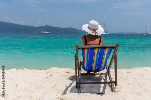 Fototapeta Naklejka Na Ścianę i Meble -  A girl in a white hat sunbathing in a deckchair and looking into