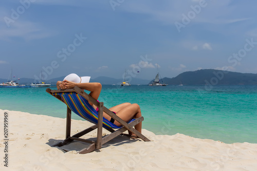 A girl in a white hat sunbathing in a deckchair and looking into