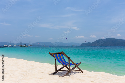 A beautiful empty chaise longue stands on the beach at the seaside.