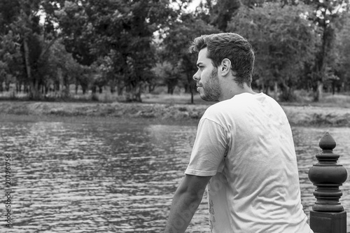 Man on a bridge over a river with the lost look