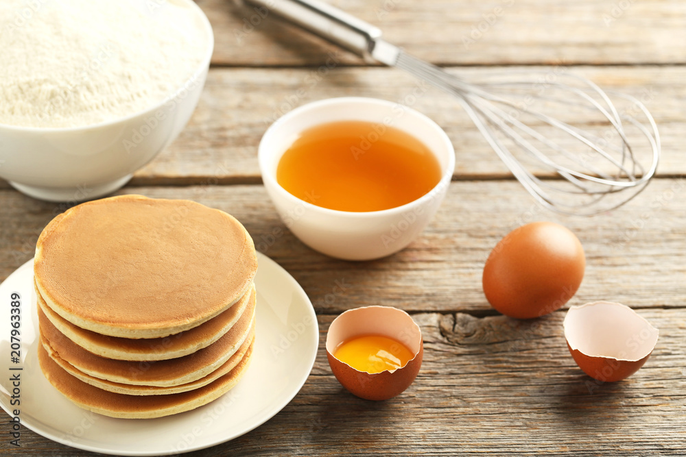 Tasty pancakes with eggs and cup of tea on grey wooden table