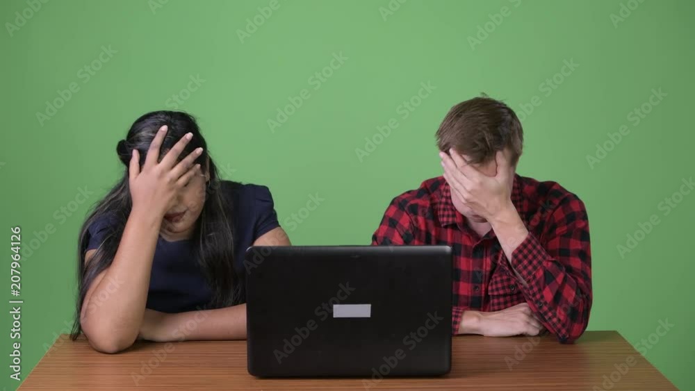 Young multi-ethnic business couple together against green background Young multi-ethnic business couple together against green background