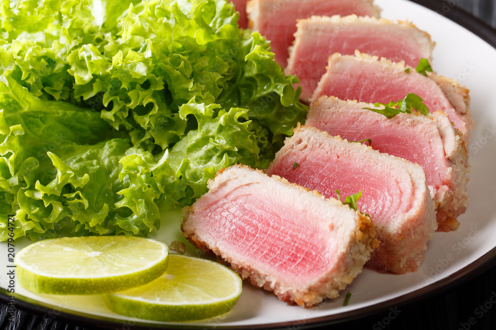 Tuna steak in breading Panko with lettuce and lime closeup. horizontal