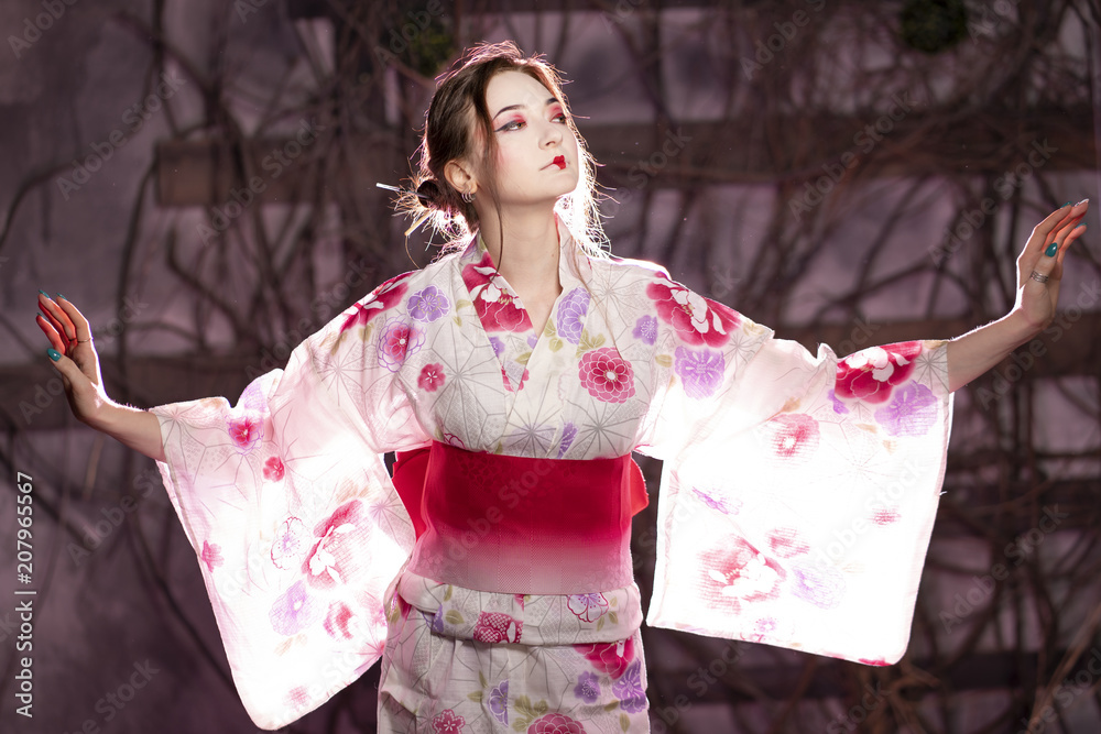 elegant girl in a classic traditional dress Japanese kimono white and pink standing alone on dark background in the studio