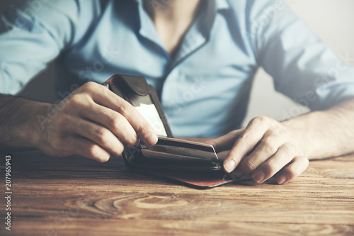 businessman showing credit card in wallet at desk