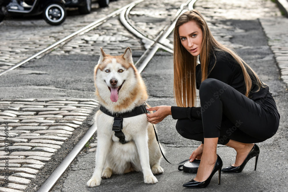 Fashionable young woman posing with dog over city background. Fashionable young woman posing with dog over city background.