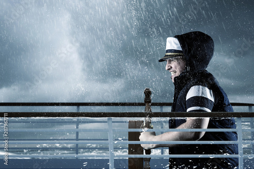 helmsman with vest and cap struggle against storm in front of stormy sea photo