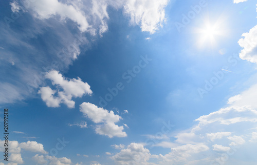 Blue sky with fluffy clouds and sun
