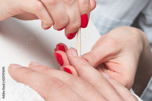Men s manicure. the hands of the beautician treated cuticle of men s hands using the orange sticks