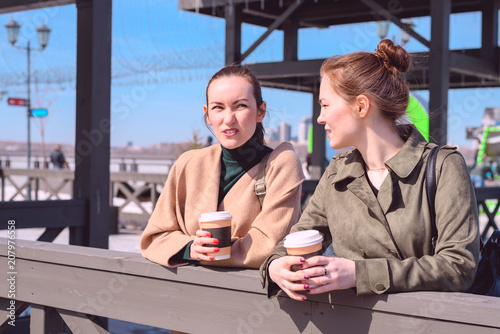 Tableau sur toile Conversation on a walk two girls with coffee in hand