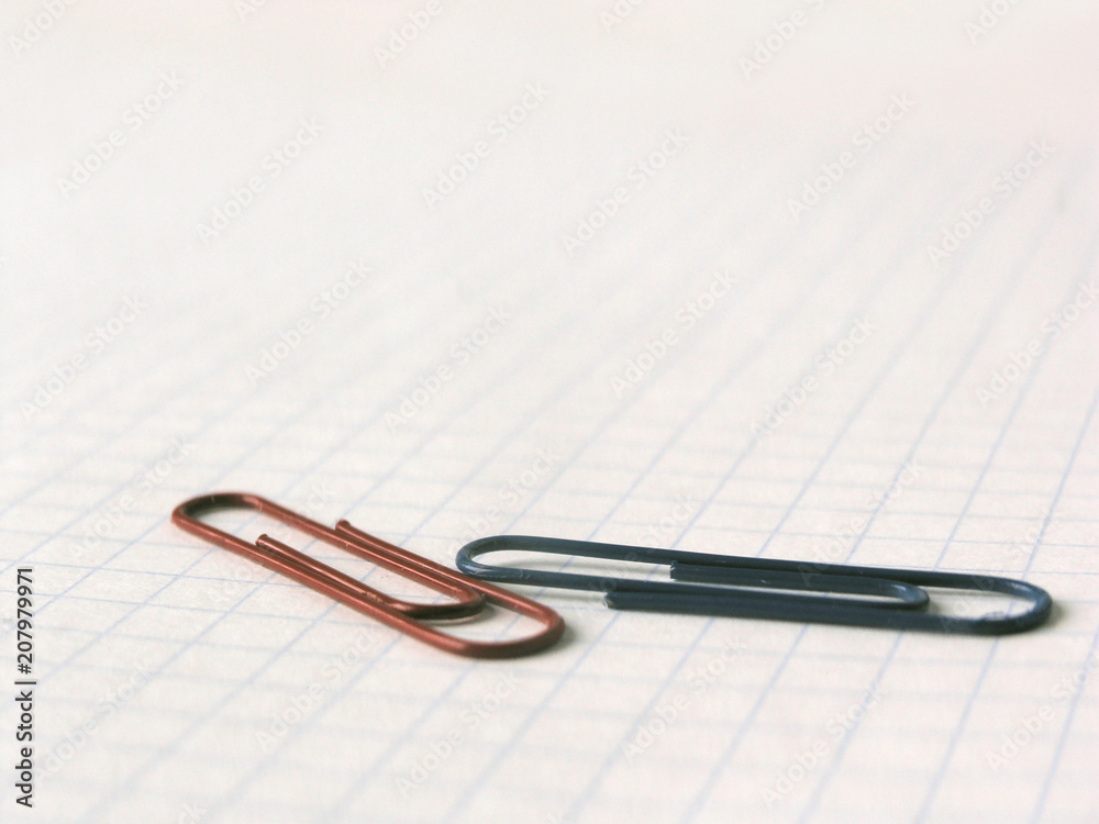 close up.blue and red paper clips on the background of notebook sheet close up.blue and red paper clips on the background of notebook sheet