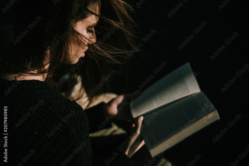 Obraz premium Young woman reading by the seaside