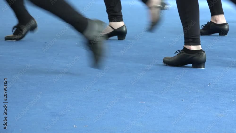 Girls feet tapping on blue carpet, tap dance Broadway style, stage at theatre. Tappers striking on blue background with shiny light. Learning musical culture, choreography at performance Girls feet tapping on blue carpet, tap dance Broadway style, stage at theatre. Tappers striking on blue background with shiny light. Learning musical culture, choreography at performance