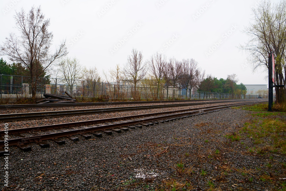 Fototapeta premium A three way rail road track in an urban environment, during the day, cloudy, rainny day.