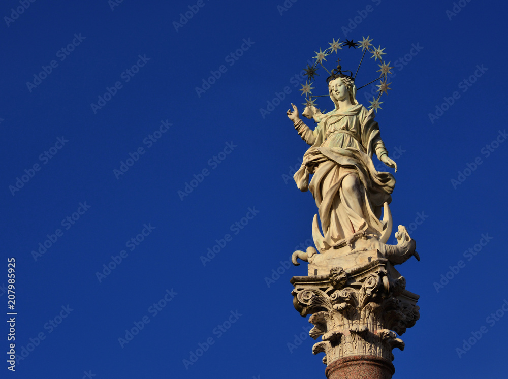 Statue of Virgin Mary of the Stars crushing dragon and crescent at the top of an ancient column in the historic center of Lucca, erected in 1687 (with copy space)