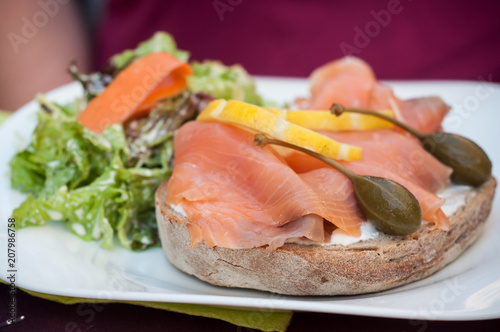 closeup of traditional salad with salmon, lemon and capers on sliced bread