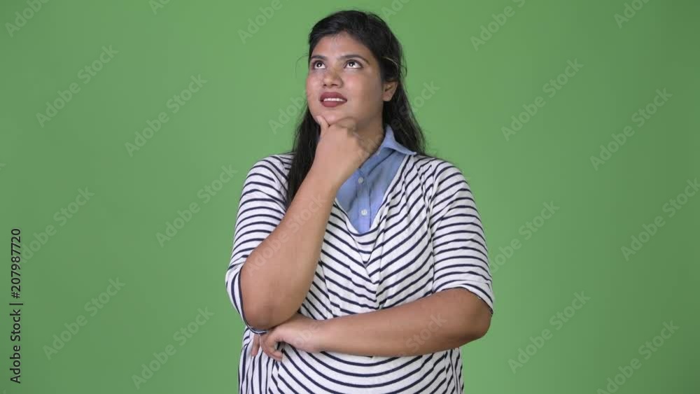 Young overweight beautiful Indian businesswoman against green background Young overweight beautiful Indian businesswoman against green background