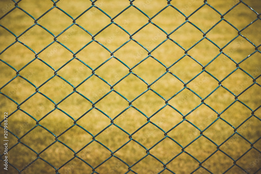 Fototapeta premium Wire fence with yellow grass on background