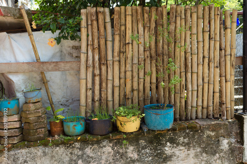 Cerca de palos de bambú y muro con macetas antiguas