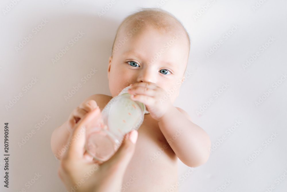 A portrait of cute newborn baby being fed by her mother using bottle A portrait of cute newborn baby being fed by her mother using bottle