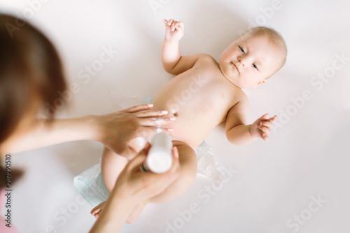 Mother preparing baby powder in her hand and four month old baby as a background photo