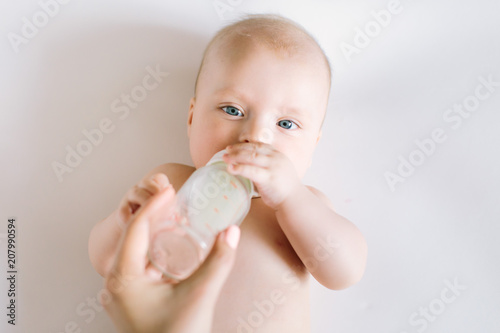 A portrait of cute newborn baby being fed by her mother using bottle