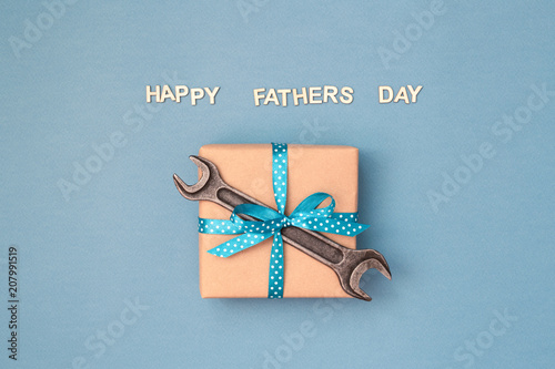 Happy Father's day card with gift box wrapped in kraft paper tied with blue r...