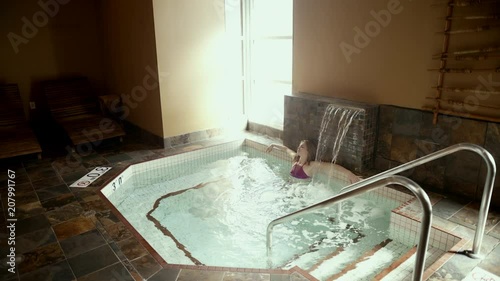 Attractive Female walking to and relaxing  in indoor hot tub then exits