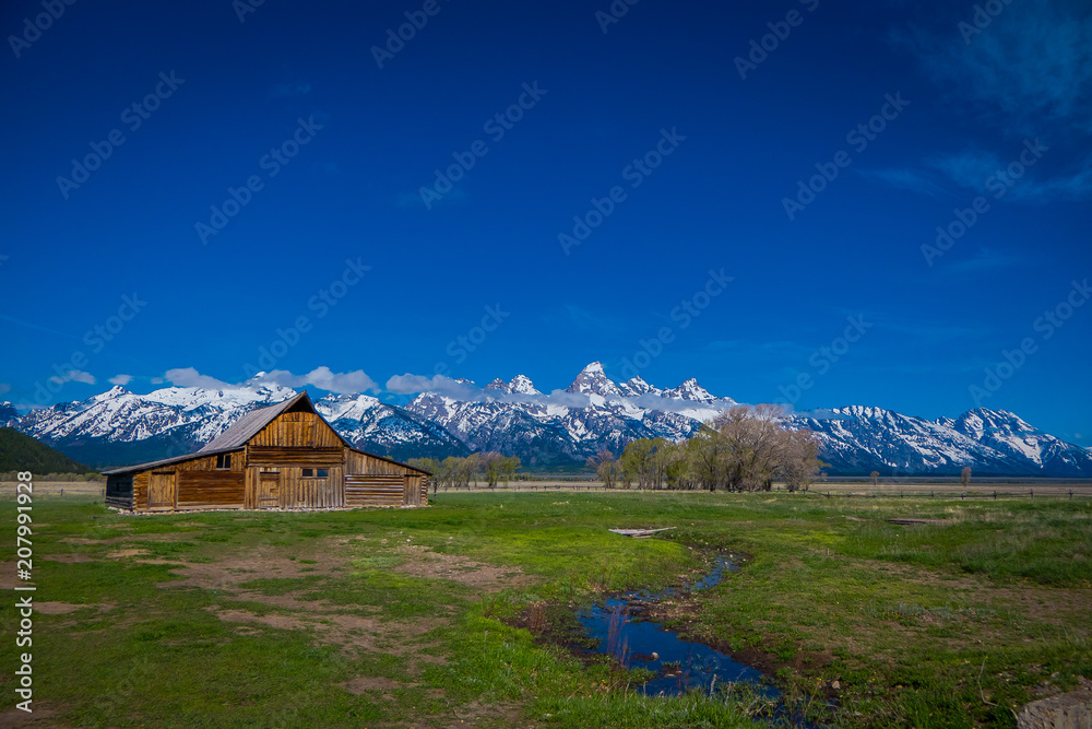 Old mormon barn in Grand Teton Mountains with low clouds. Grand Teton National Park, Wyoming