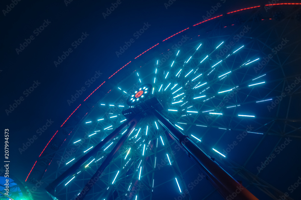 Luminous ferris wheel at night in a fog, high carousel
