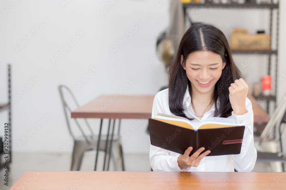 Beautiful of portrait business asian young woman reading on notebook with success on table, girl looking note excited at coffee shop, freelance and education concept. Beautiful of portrait business asian young woman reading on notebook with success on table, girl looking note excited at coffee shop, freelance and education concept.
