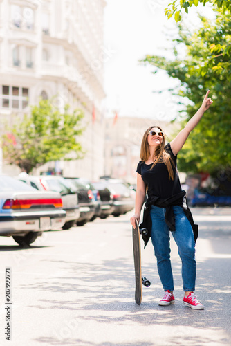Joyful female skater holding a skateboard in the city © qunica.com