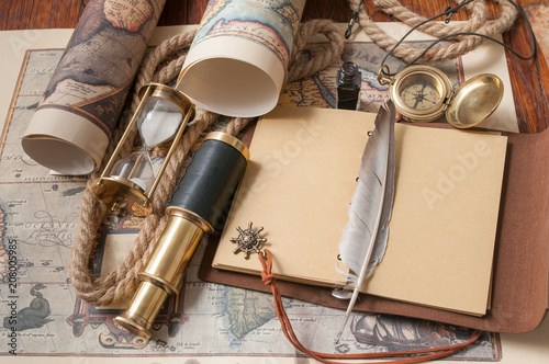 Quill pen and a notebook with old rolled papers, maps and vintage items