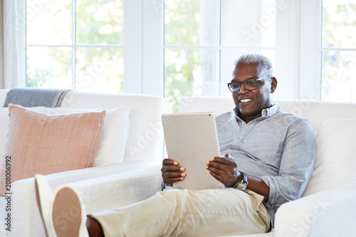 Happy African American Senior man Browsing the internet on a large digital tablet photo